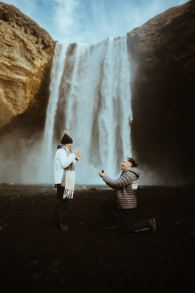 Guy proposing to his girlfriend under skogafoss waterfall in Iceland